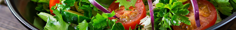primer plano de ensalada con hojas de perejil, rodajas de tomates, cebolla y pepino