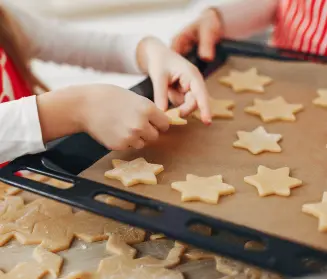 manos de niño colocando galletas de estrella en una bandeja de horno